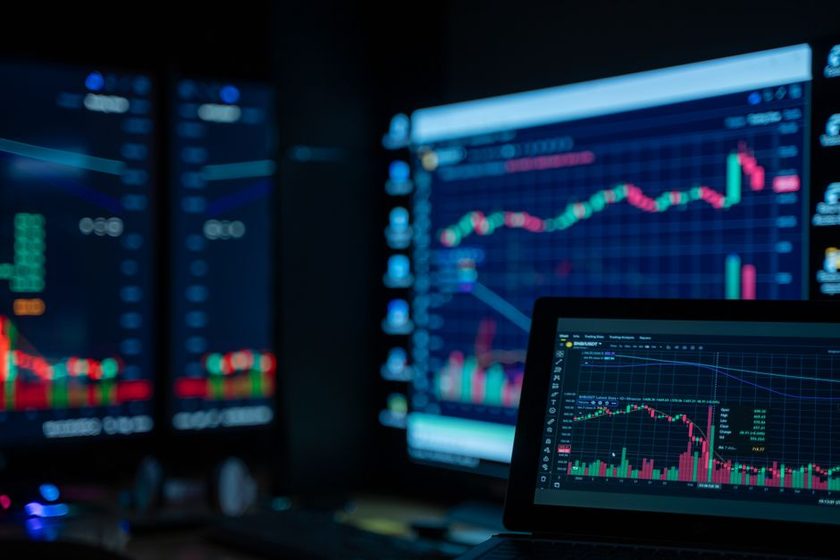Telas escuras exibindo gráficos de candles e cotações financeiras num ambiente de monitoramento de investimentos.